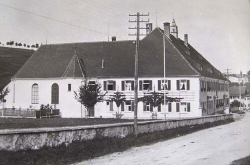 Großes historisches Gebäude mit Satteldach, mehreren Fenstern und einem kleinen Turm im Hintergrund